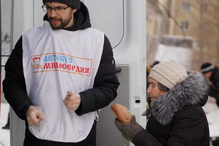 Волонтёр «Автобуса милосердия» раздаёт хлеб